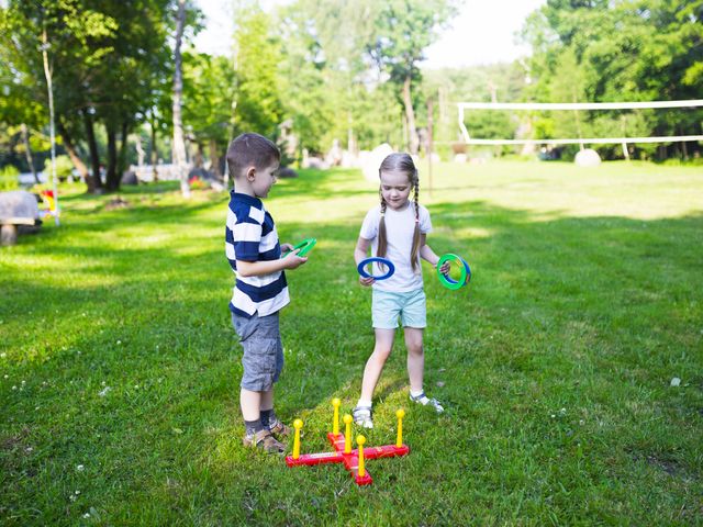 Two children playing a ring game on a grassy outdoor play area